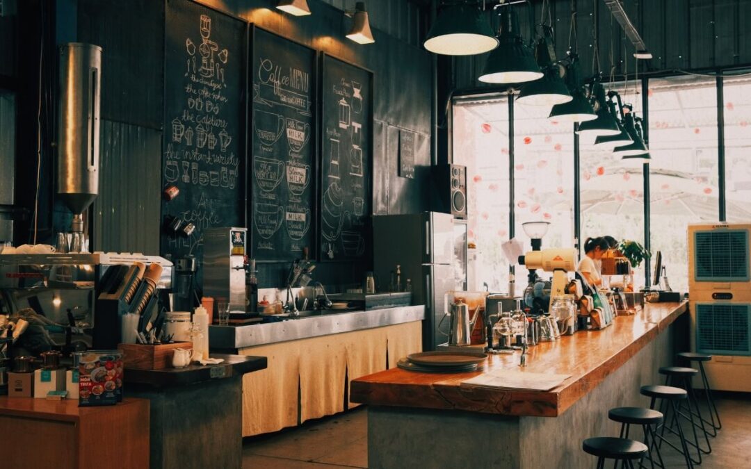 Small commercial space design in a compact London café with banquette seating, warm lighting and a slim service counter.